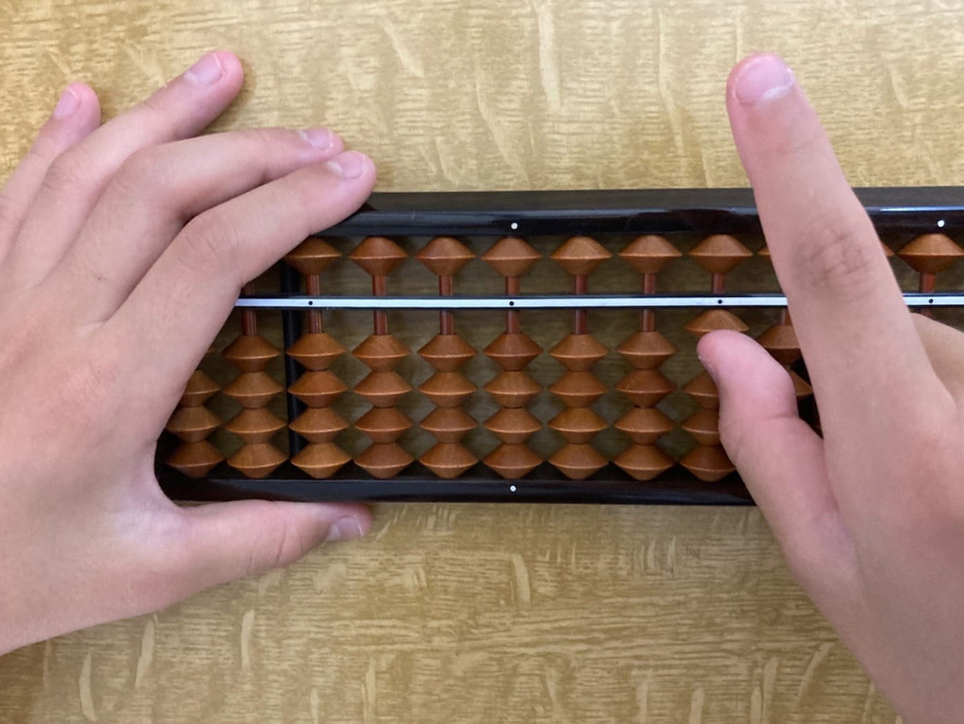 そろばんに子供が手を置いた写真